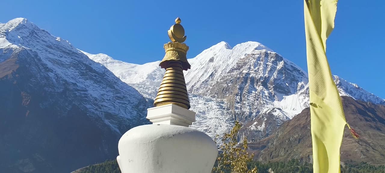 Buddhist stupa and prayer flag with snow-capped Annapurna Himalayan mountains in Nepal