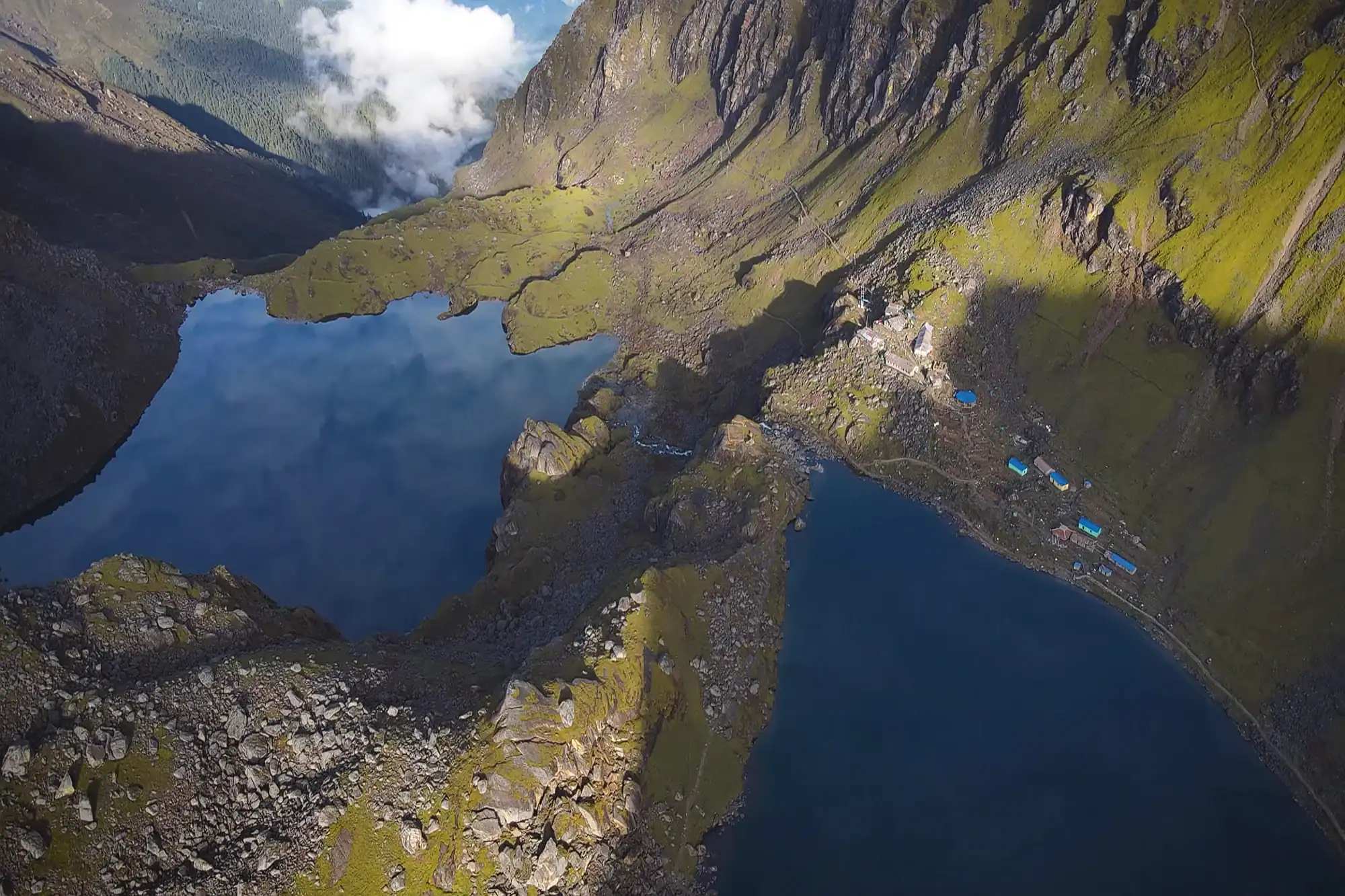 Aerial view of holy Gosaikunda alpine lakes and mountain lodge village nestled among rocky Himalayan peaks in Nepal.