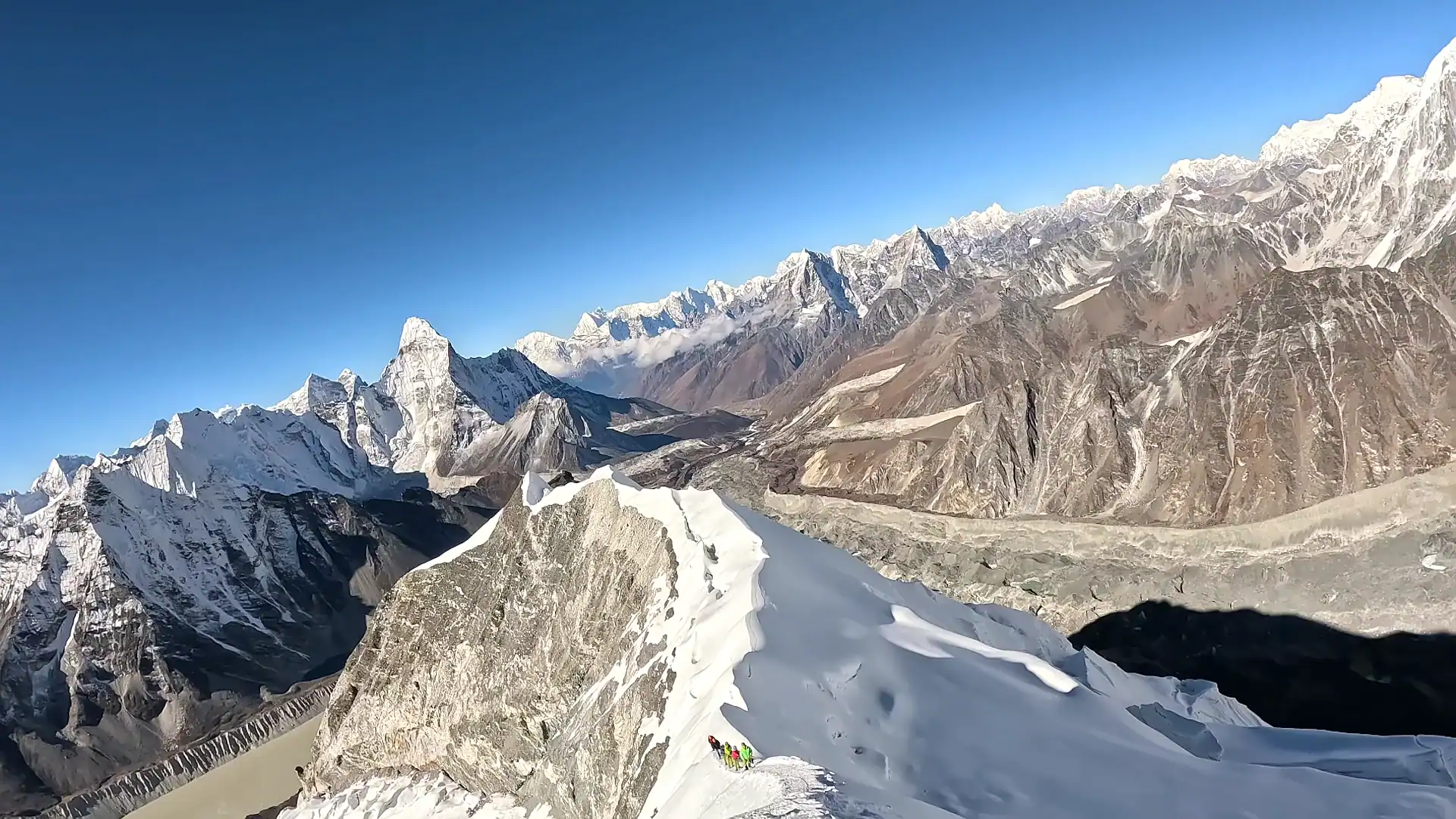 Climbers traversing a snowy ridge in the Nepal Himalayas with Ama Dablam in the background