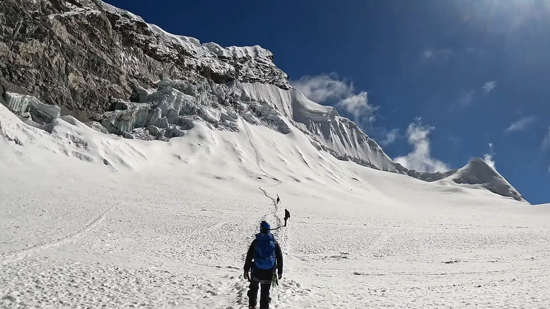 Mountaineers trekking up a steep snowy glacier slope during a high-altitude alpine expedition