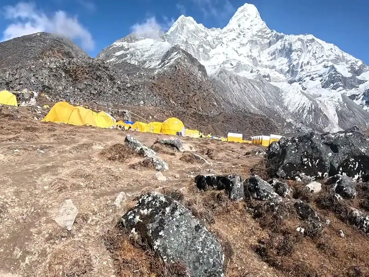 Yellow expedition tents at a Amadablam base camp with snow-covered mountain peaks in Nepal