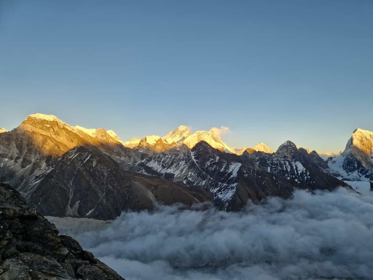 Sunrise over snow-capped Himalayan mountain peaks rising above a sea of clouds in Nepal.